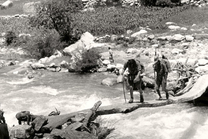 Ein Expeditionsteilnehmer und ein afghanischer Soldat überqueren einen Wildbach.