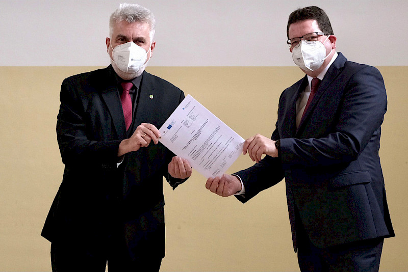 Wissenschaftsminister Armin Willingmann (links) übergibt einen Förderbescheid an Rektor Christian Tietje.