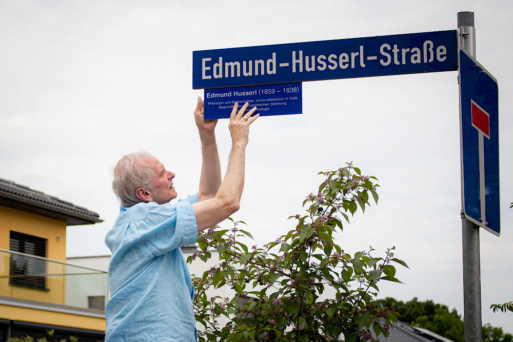 Reinhold Sackmann bringt die Tafel am Straßenschild in Halle-Dölau an.